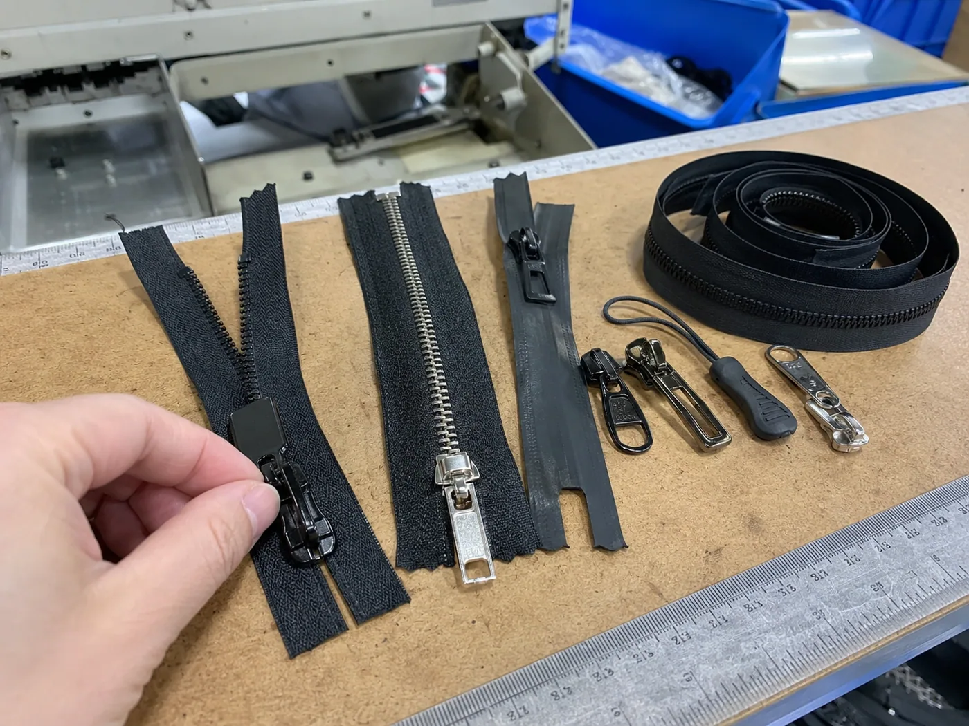 Smartphone-style QC desk showing nylon, metal, waterproof, and coil zippers with puller samples and ruler