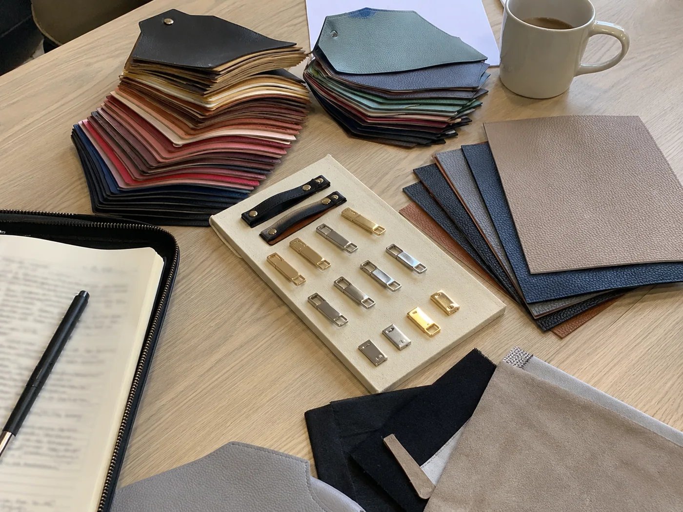 Smartphone-style French sourcing review desk with premium handbag swatches, lining samples, zipper options, blurred notes, and coffee cup